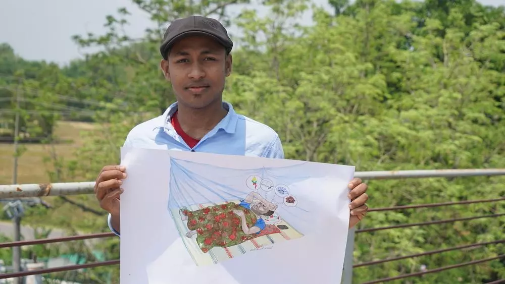 A Rohingya man posing with his artwork in a refugee camp in Cox's Bazar, Bangladesh