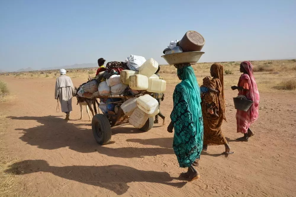 A family carries their belongings as they are forced to move due to the ongoing conflict in Sudan