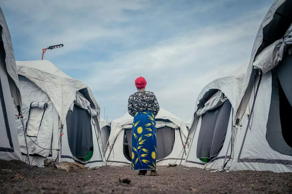 A female patient stands between tents set up to treat victims and survivors of sexual violence