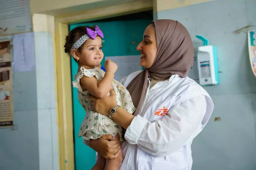An MSF health promotion team member holds a young child receiving follow-up care at Al-Mahdi health centre in Sadr City. 