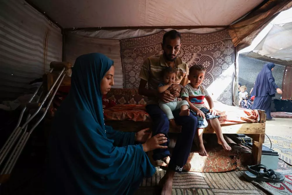 A patient holds his children as his wife massages his amputated leg to relieve phantom limb pain.