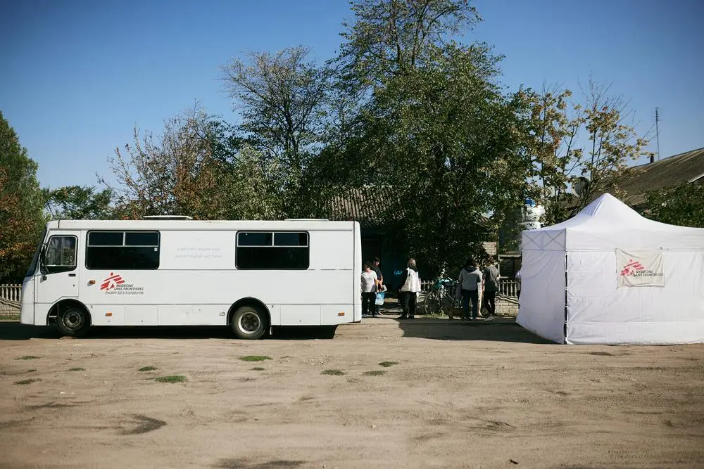 A Doctors Without Borders vehicle and tent posted in front of houses in a frontline community neighbourhood.