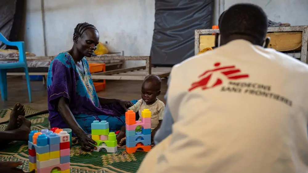 A mother playing with her kid in MSF's Inpatient Therapeutic Feeding Center (ITFC) in Ethiopia