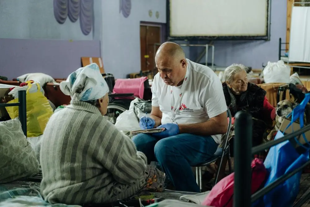 an MSF staff member sits with people who have been displaced from areas near the frontlines in Ukraine