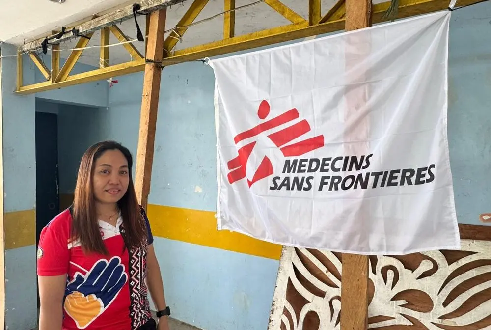 Teacher next to MSF banner